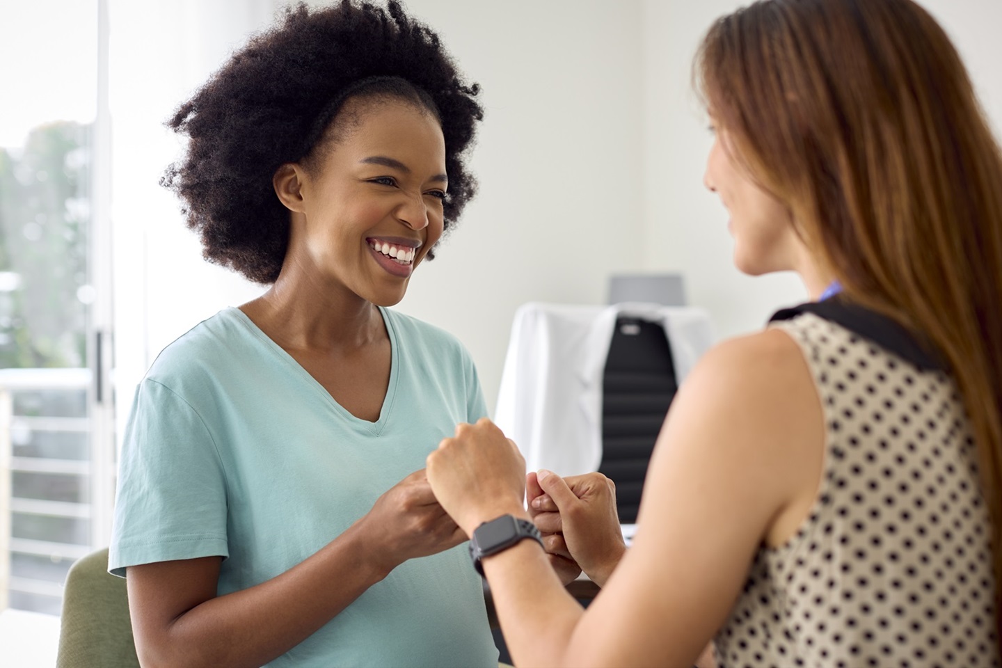 Smiling Pregnant Woman At Appointment With Female Doctor Or GP In Office